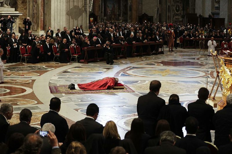 Pope Francis prostrates in prayer Friday during the Good Friday Passion of Christ service inside St. Peter’s Basilica at the Vatican. With security heightened, the pope later attended the traditional Way of the Cross procession at the ancient Colosseum in Rome with 20,000 faithful in attendance.  
