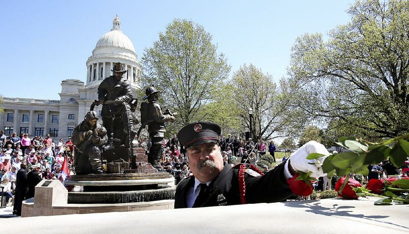Little Rock Firefighter Charles Austin places a rose as the names of fallen firefighters are called out Saturday during the Arkansas Fallen Firefighters Memorial Service at the state Capitol in Little Rock.