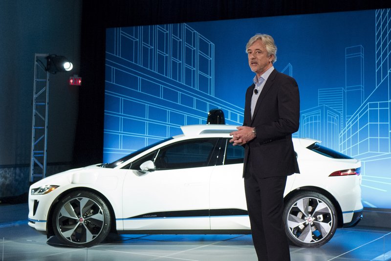 John Krafcik, the CEO of Waymo, stands with the Jaguar I-Pace vehicle, Tuesday, March 27, 2018, in New York. Self-driving car pioneer Waymo will buy up to 20,000 of the electric vehicles from Jaguar Land Rover to help realize its vision for a robotic ride-hailing service. The commitment announced Tuesday marks another step in Waymo's evolution from a secret project started in Google nine years ago to a spin-off that's gearing up for an audacious attempt to reshape the transportation business. (AP Photo/Mark Lennihan)