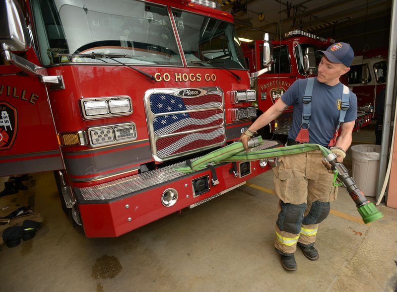 NWA Democrat-Gazette/ANDY SHUPE Martin Striefler, firefighter with the Fayetteville Fire Department, rewinds a hose Thursday in the department's central fire station. The City Council will take up a proposal Tuesday for citywide raises, which includes a new pay structure for police and firefighters.