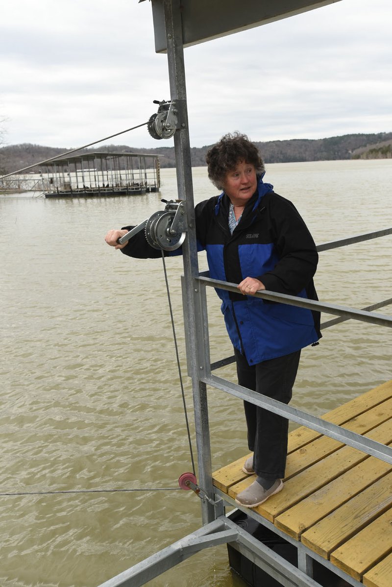 Mary Loots shows Saturday how cables and winches on their dock at Beaver Lake near Rocky Branch park are used to move the dock as the lake level rises and falls. The Army Corps of Engineers will accept public comment this month on a new shore-line management plan for the lake.