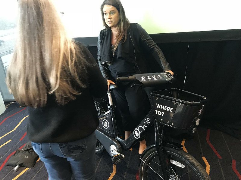 Bantam Strategy Group President and CEO Lindsey West shows off an example of what the bicycles will look like in the planned bike-sharing program for Little Rock and North Little Rock. Officials have still not signed a contract but hope to launch the program in the spring of 2019.

