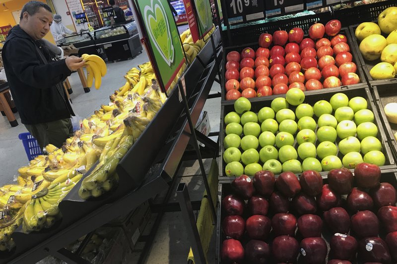 A man chooses bananas near imported apples from the United States at a supermarket Monday in Beijing. China on Monday imposed  $3 billion in previously announced tariffs on 128 imported goods, including apples originating in the U.S.
