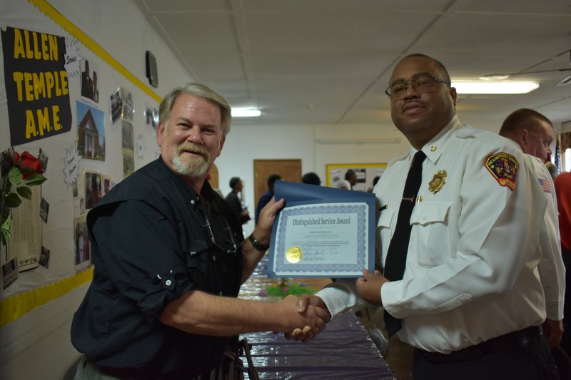 Larry Potter, a photographer for KATV, Little Rock's ABC affiliate, shakes hands with Pine Bluff Fire Chief Shauwn Howell after being presented with a distinguished service award for his assistance at the scene of an apartment fire on March 7, 2018.