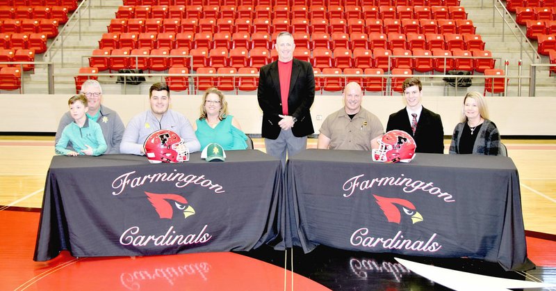 Pam Jowers Special to the Enterprise-Leader Farmington seniors Zach Newman (left behind Cardinal helmet) with his parents, Willie and Stephanie Newman, accompanied by ; and Jacob Gray (right behind helmet) with his parents, Bill and Karen Gray; signed national letters of intent to continue their football careers in college on Feb. 7. Farmington head coach Mike Adams (standing) introduced the players. Newman signed as an offensive lineman with Arkansas Tech while Gray signed as an "H-back" with Henderson State.