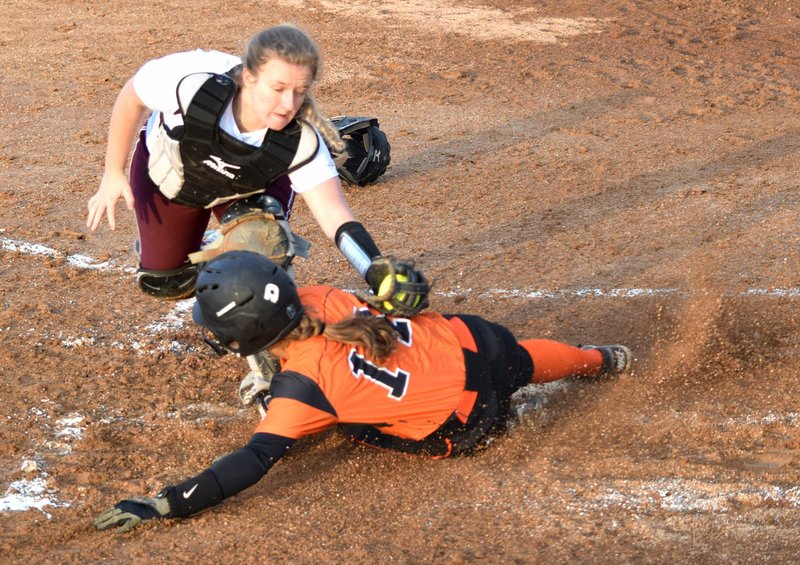 Westside Eagle Observer/MIKE ECKELS Gravette's Lizzy Ellis slides into home plate as Gentry catcher Alexis Droddy tags her during the fourth inning of the Gravette-Gentry softball game at Lion Softball Field in Gravette March 29. The home plate umpire ruled that Ellis crossed home plate before the tag.