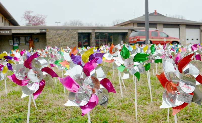 Keith Bryant/The Weekly Vista Bella Vista police officers and firefighters teamed up with volunteers Monday to place 380 pinwheels, each representing a confirmed case of child abuse in Benton County, in front of the Bella Vista Police Department. This is down from last year, which had 439 confirmed cases.