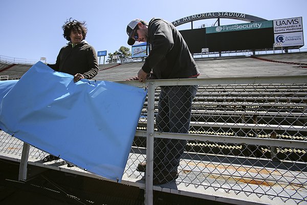 Stadium workers Hugo Arias (left) and Josh Oliver (right) hang signs in the end zone of War Memorial Stadium on Wednesday, April 4, 2018, in preparation for the Arkansas Razorbacks' Red-White game on Saturday in Little Rock. War Memorial Stadium recently launched a new website, brand and veterans tributes. It is part of the stadium's next phase of development under the supervision of the Arkansas Department of Parks and Tourism.