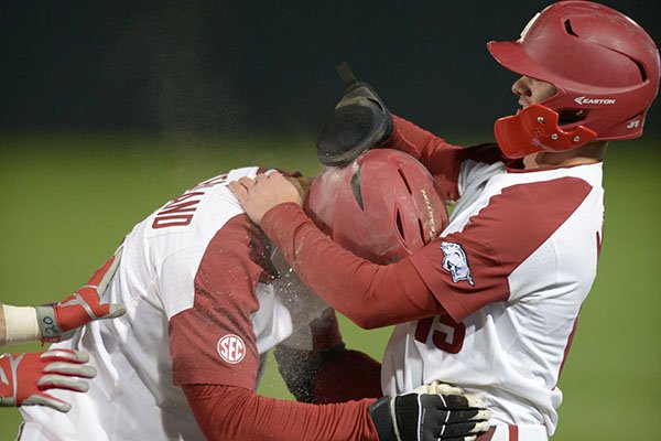 Arkansas third baseman Casey Martin (right) and first baseman Jordan McFarland celebrate Tuesday, April 3, 2018, after Martin scored the game-winning run during the 10th inning on a ball hit by McFarland at Baum Stadium in Fayetteville.