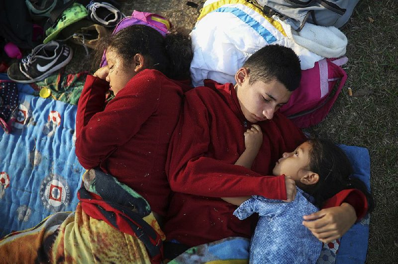 Anderson Zelaya (center) and his sister, Daniela, rest with others Wednesday at a soccer field in Matias Robero in Mexico’s Oaxaca state as they and their family await temporary transit visas that would get them to the U.S. border and a chance to request asylum and join relatives in New York.  