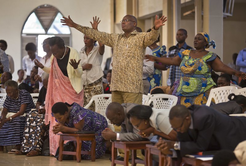 FILE - In this Sunday, April 6, 2014 file photo, Rwandans sing and pray at the Evangelical Restoration Church in the Kimisagara neighbourhood of the capital Kigali, Rwanda. Rwanda's government in 2018 is closing thousands of churches and dozens of mosques as it seeks to assert more control over a vibrant religious community whose sometimes makeshift operations, authorities say, have threatened the lives of followers. (AP Photo/Ben Curtis, File)