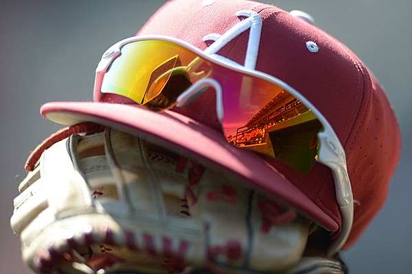 An Arkansas hat and glove sit in the dugout prior to a game against Louisiana-Monroe on Wednesday, April 4, 2018, in Fayetteville.