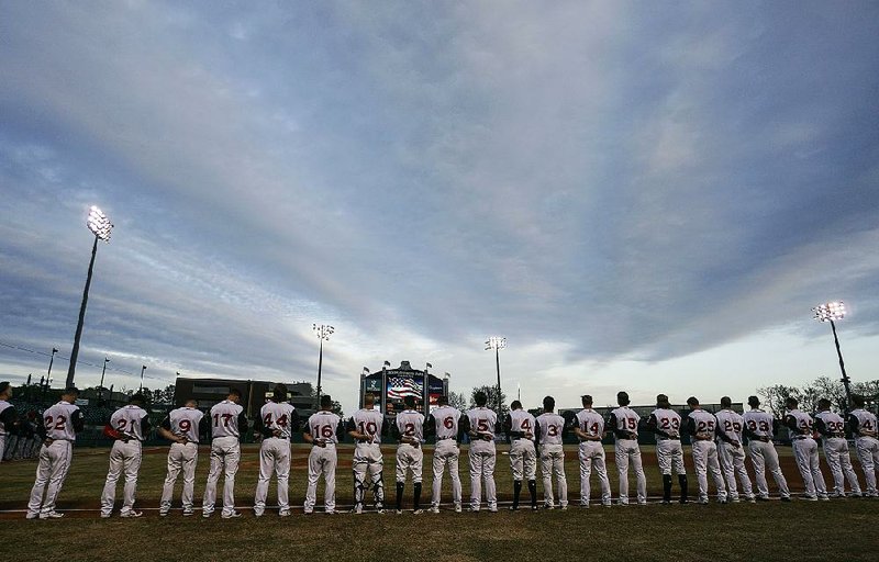 Members of the Arkansas Travelers stand along the first-base line during the national anthem at Dickey-Stephens Park in North Little Rock before Thursday night’s season-opening game against the San Antonio Missions. The Travs won 3-1.
