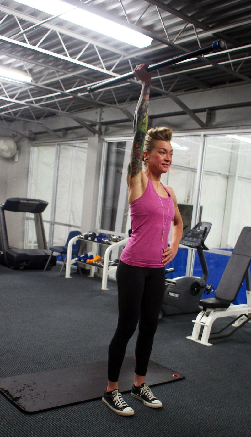 Fitness instructor Lindsay Petruk does step 1 of the Barbell Knee Ups exercise 
