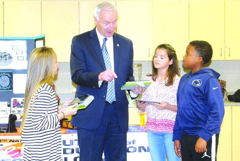 From left, Brintley Parker, Gov. Asa Hutchinson, Juana Reichhardt and Isaiah Singleton show the governor how they programmed drones to fly on their own by coding. The students are in the sixth grade at Washington Middle School. Kaitlyn Rigdon/News-Times