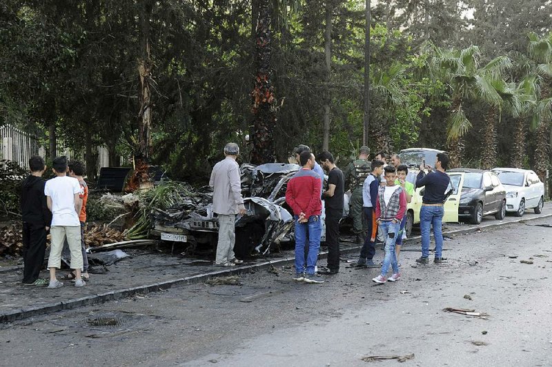 Syrians gather after shelling by a rebel group destroyed vehicles Friday in Damascus’ Rabwa neighborhood.  