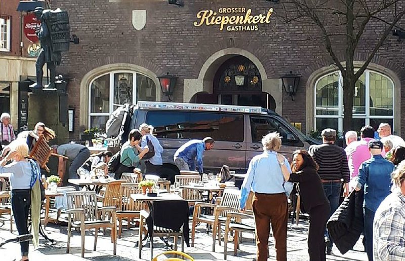People stand in front of a restaurant in Muenster, Germany, on Saturday after a vehicle crashed into a crowd.