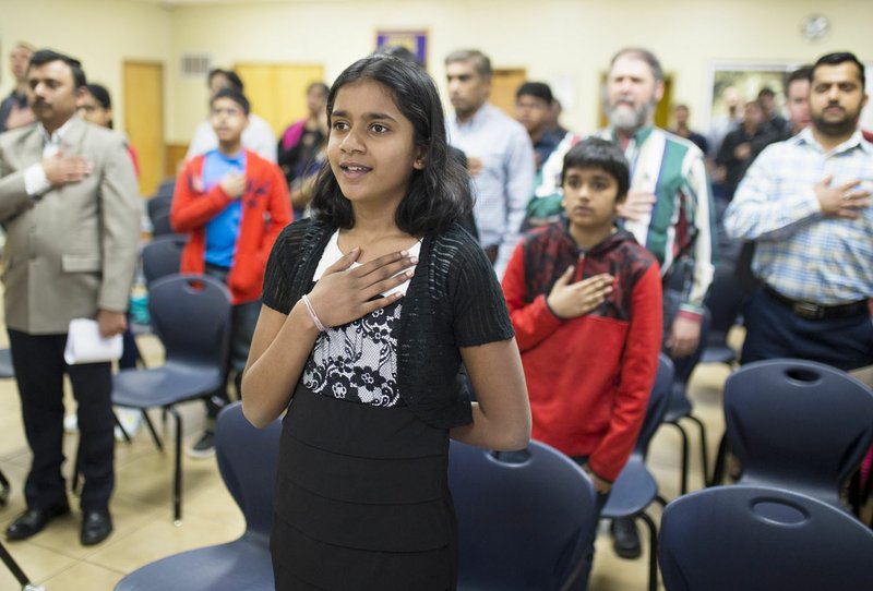 Trishika Chintakunta, 11, of Bentonville joins in reciting the Pledge of Allegiance at Centerton City Hall during a March 17 meeting held to raise awareness about the plight some immigrants, including Trishika and her sister Vanshika, 14, face.