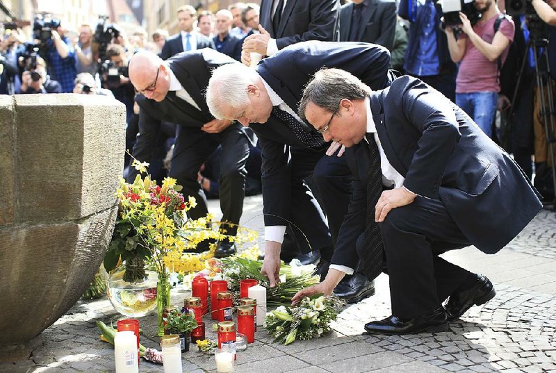The mayor of Muenster, Germany, Markus Lewe (from left); German Interior Minister Horst Seehofer; and North Rhine-Westphalia Gov. Armin Laschet place flowers in front of a fountain in Muenster on Sunday.