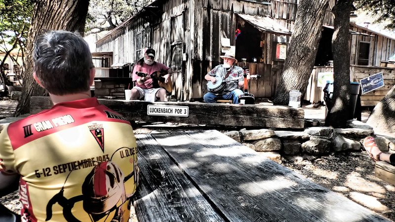 Bike riders enjoy music and barbecue in Luckenbach, Texas during a Texas Hill Country cycling trip.