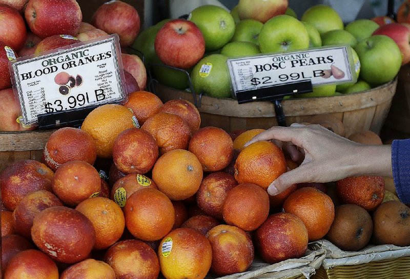 A customer reaches for an orange at Buffalo Whole Food & Grain Co. in San Francisco recently. U.S. wholesale prices rose in March, reflecting broad increases in the costs of food, services and goods, the Labor Department said Tuesday. 