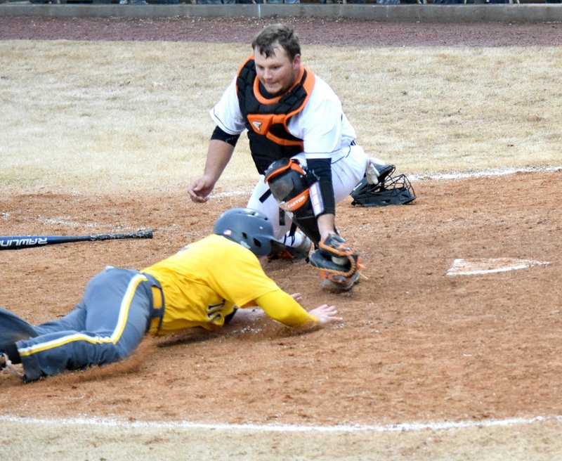 Westside Eagle Observer/MIKE ECKELS In a perfect defensive move, Gravette catcher Kenton Tajchman holds the ball in front of a Tiger runner sliding into home plate during the April 2 Gravette-Prairie Grove baseball game in Gravette for the out.