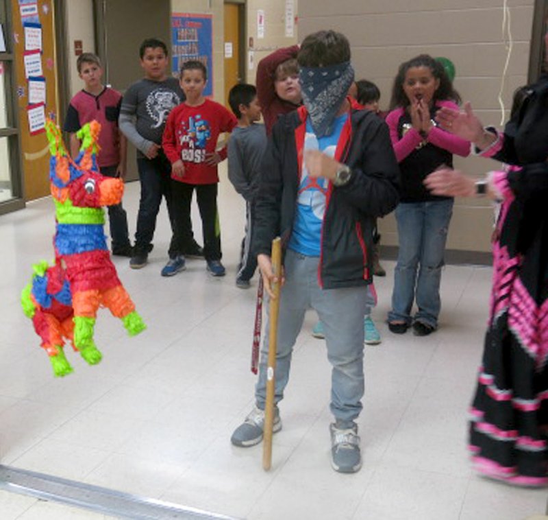 Westside Eagle Observer/SUSAN HOLLAND Students line up and wait their turn at striking the pinata at the GUE multicultural dinner Thursday, April 5, as one blindfolded young man prepares to take a whack at the colorful, candy-filled donkey.