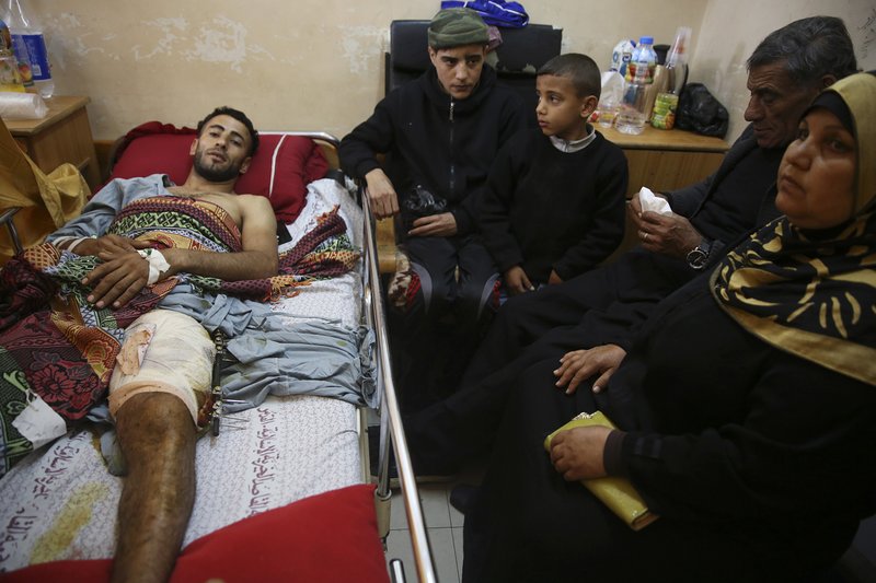 In this Monday, April 9, 2018 photo, Raed Jadallah, a Palestinian 25-year-old surfer, lies on a bed as his father, mother and brothers visit him, at the Shifa hospital in Gaza. Jadallah is among the nearly 1,300 people that Palestinian health officials said have been shot and wounded by Israeli soldiers during mass border protests over the past two weeks. The casualty figures are at the heart of an intensifying debate over the military's open-fire orders. (AP Photo/Adel Hana)