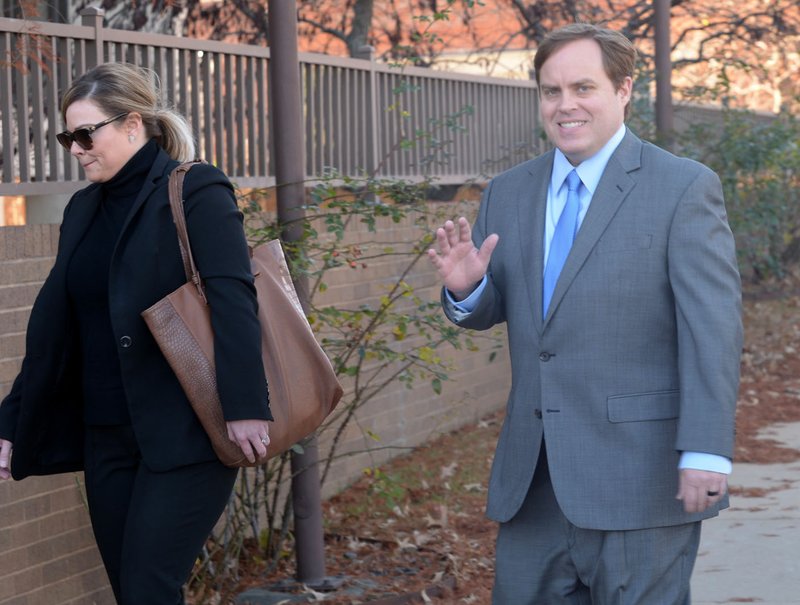 Former state Sen. Jon Woods (right), surrounded by members of his legal team, waves Nov. 30 as he walks into the John Paul Hammerschmidt Federal Building in Fayetteville.
