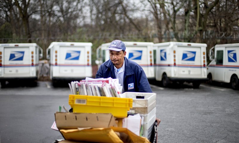 In this Feb. 7, 2013 file photo, U.S. Postal Service letter carrier Michael McDonald gathers mail to load into his truck before making his delivery run in the East Atlanta neighborhood, in Atlanta. After weeks of railing against online shopping giant Amazon, President Donald Trump signed an executive order Thursday, April 12, 2018, creating a task force to study the United States Postal System. 