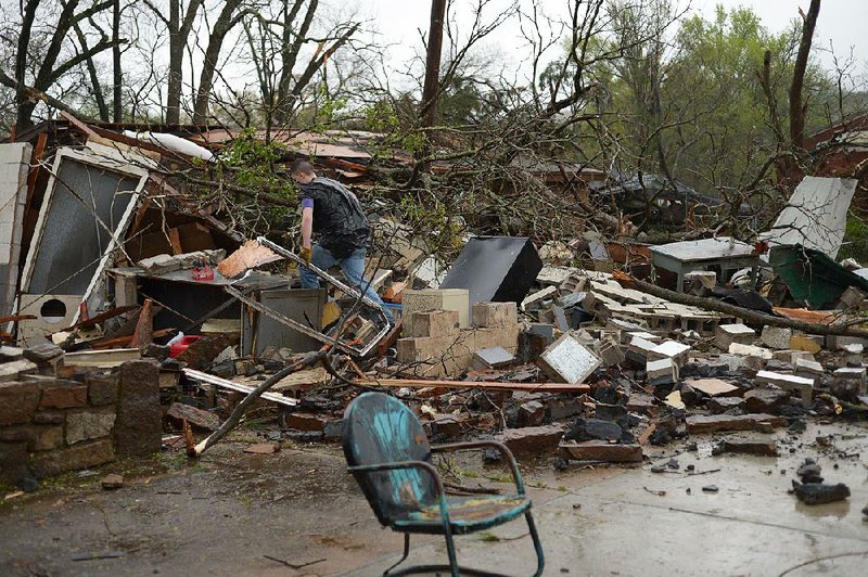 Matt Kimes of West Fork sifts the rubble of a garage and home owned by his grandmother, Farnese Kimes, in downtown Moun-tainburg after a tornado swept through Friday.