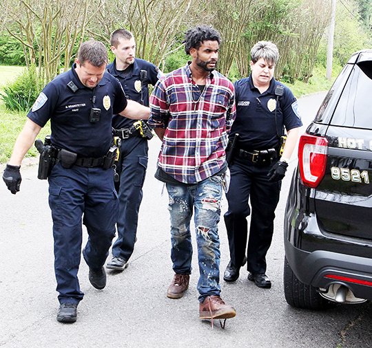 The Sentinel-Record/Richard Rasmussen SWIFT CAPTURE: Hot Springs police Officer 1st Class Brian Branstetter, left, and Sgt. Sonia Luzader, far right, escort a suspect, identified as Joseph D. Brown, 29, of Hot Springs, to a waiting unit moments after he was arrested for allegedly stealing a pickup truck.