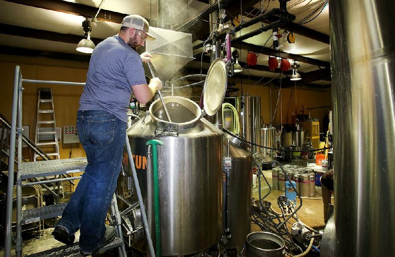 Chris Courtney, a brewer at Fossil Cove in Fayetteville, stirs a mash last week at the company’s Birch Avenue base. The brewery is moving some of its operation about a half block away to Poplar Street.