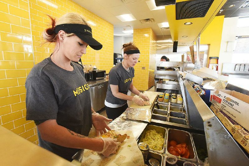 Crystal Farrington (left) and Celeastina Melbourne make sandwiches during training last week at Which Wich in Bentonville.