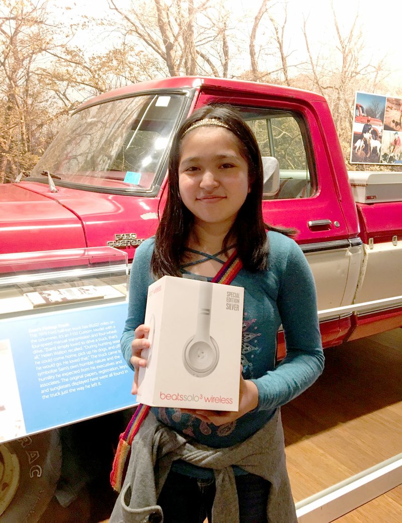 Photo submitted Ruby Vega, seventh-grade student at Siloam Springs Middle School, was one of five students to win The Walmart Museum's national essay contest celebrating Sam Walton's 100th Birthday. She is pictured in front of Walton's truck in the museum with her prize, a pair of special Spark Edition Beats by Dre' headphones.