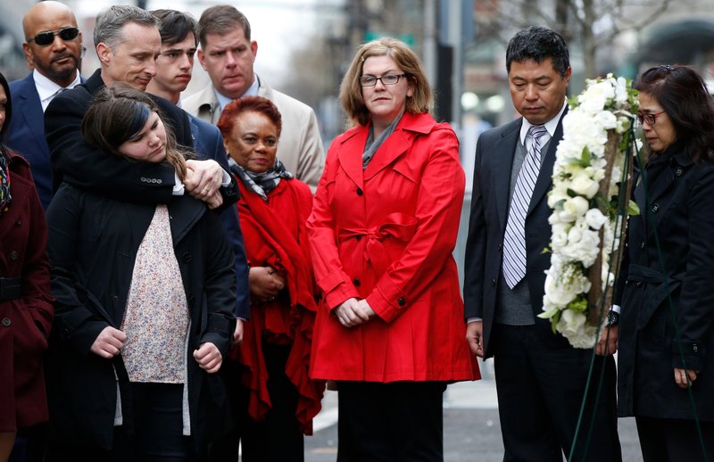 The father of Lingzi Lu, Jun Lu, second from right, and her aunt Helen Zhao, right, observe a moment of silence with the family of Martin Richard, foreground from left, Bill, Jane, Henry and Denise, center, during a ceremony at the site where Martin Richard and Lingzi Lu were killed in the second explosion at the 2013 Boston Marathon, Sunday, April 15, 2018, in Boston. (AP Photo/Michael Dwyer)