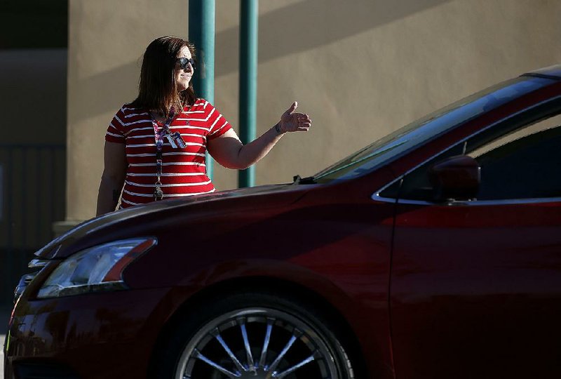 Stefanie Lowe, a teacher at Tuscano Elementary School, waves on arriving cars as part of her traffic duties at school, after joining other teachers, parents and students as they stage a “walk-in” for higher pay and school funding Wednesday in Phoenix