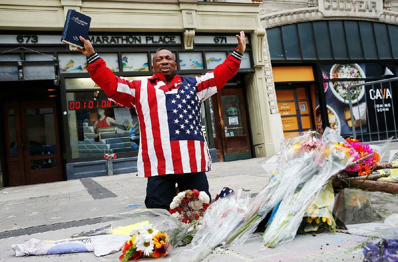 Cristopher Nzenwa, of Boston, prays at the site of the ﬁrst explosion during the 2013 Boston Marathon on Sunday. Today’s running of the Boston Mara-thon comes ﬁve years after the bombing.