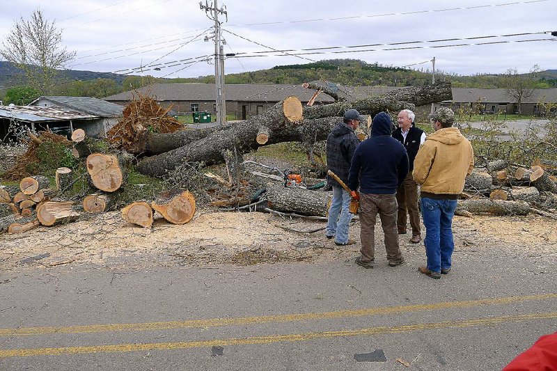 Gov. Asa Hutchinson (facing camera) talks to volunteers who were helping clear trees Sunday after a tornado hit Mountainburg on Friday. Hutchinson toured the tornado damage Sunday morning and praised the emergency response.