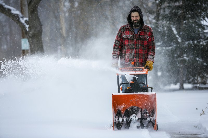 Mike Haydon snow blows the sidewalk near his home during a storm Sunday, April 15, 2018, in southwest Rochester, Minn. A deadly storm system moving through the central and southern U.S. has dumped a thick blanket of snow on parts of Minnesota, Wisconsin and South Dakota and left parts of Michigan an icy mess. (Joe Ahlquist/The Rochester Post-Bulletin via AP)