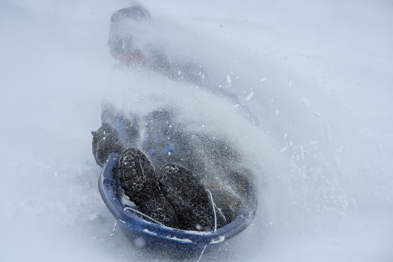Nolan Robinson, 10, of Rochester, Minn., is covered in snow at Judd Park while sledding during a storm, Sunday, April 15, 2018, in Rochester, Minn. A deadly storm system moving through the central and southern U.S. has dumped a thick blanket of snow on parts of Minnesota, Wisconsin and South Dakota and left parts of Michigan an icy mess. (Joe Ahlquist/The Rochester Post-Bulletin via AP)