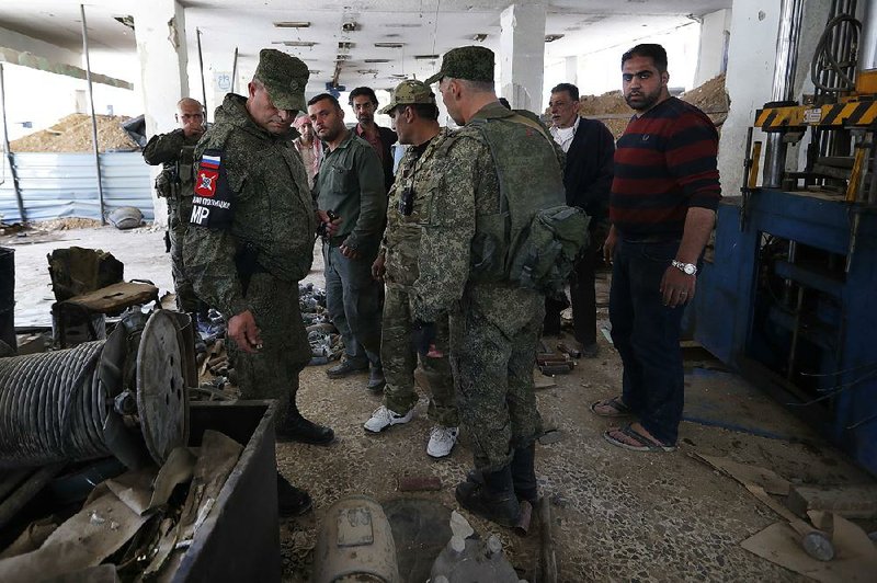 Russian military police examine weapons Monday left behind by members of the Army of Islam group in a factory that produced weapons in Douma, the site of a suspected chemical weapons attack near Damascus, Syria.