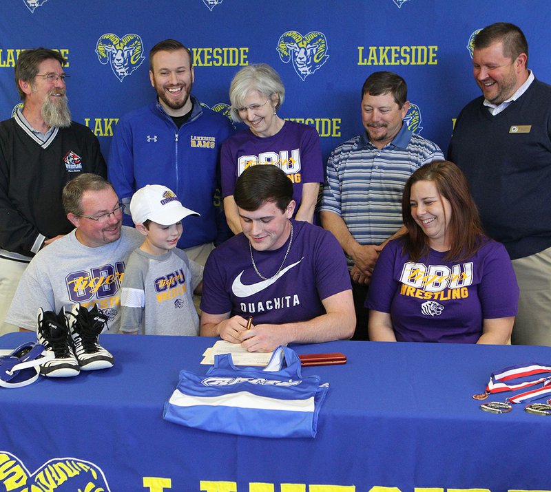 The Sentinel-Record/Richard Rasmussen TIGER TOUGH: Lakeside senior Judson Spellings, seated third from left, signs a national letter of intent to wrestle for Ouachita Baptist University Monday at Lakeside High School. With Spellings, from left, in front are his father Jason Powell, his brother Trace Powell and his mother Keri Powell, and back, from left, assistant coach Tony Bradley, assistant coach Nick Ballard, his grandmother Phyllis Spellings, head coach H.E. Burchard and Lakeside High School Principal Darin Landry.