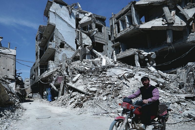 The Associated Press DESTRUCTION IN DOUMA: A man rides past destruction in the town of Douma, the site of a suspected chemical weapons attack, Monday near Damascus, Syria. Faisal Mekdad, Syria's deputy foreign minister, said on Monday that his country is "fully ready" to cooperate with the fact-finding mission from the Organization for the Prohibition of Chemical Weapons that's in Syria to investigate the alleged chemical attack that triggered U.S.-led airstrikes.