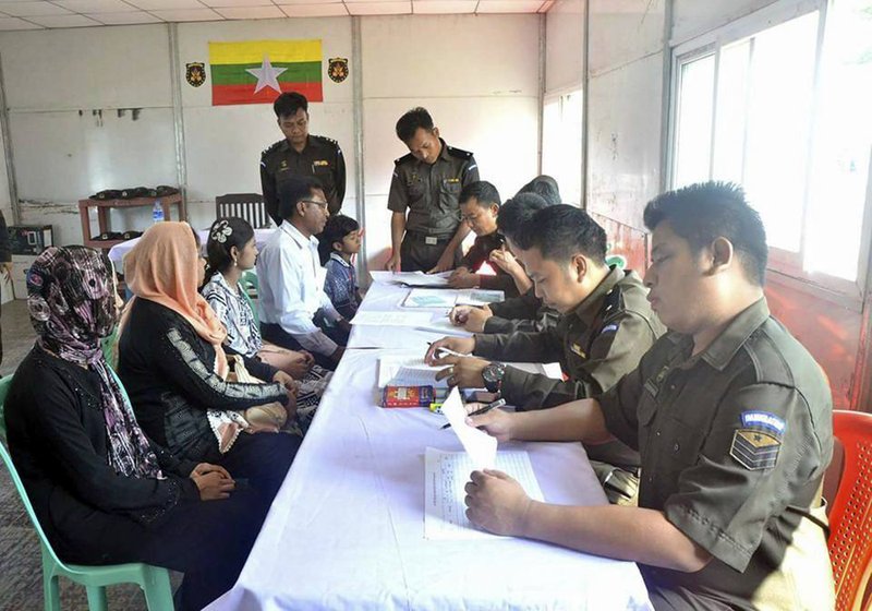 In this April 14, 2018, photo provided by Myanmar Government Information Committee, Myanmar immigration officials examine documents as a Rohingya family of five look on at a receiving center in Taung Pyo, Letwe, northern Rakhine state. Myanmar has accepted what appears to be the first five among some 700,000 Rohingya Muslim refugees who fled military-led violence against the minority group, even though the U.N. says it is not yet safe for them to return home. (Myanmar Government Information Committee via AP)