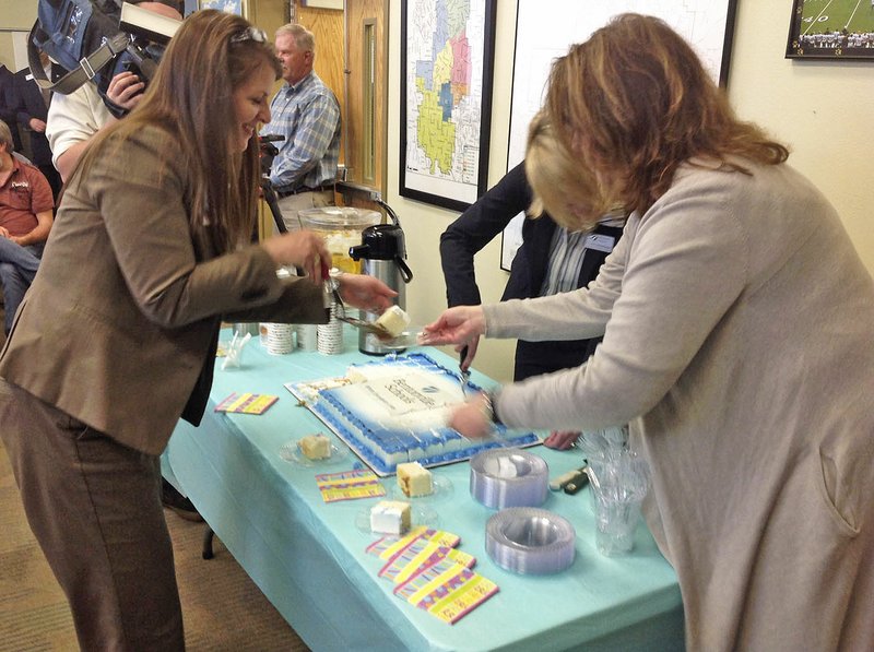 Bentonville Schools administrators Jennifer Morrow (from left), Janet Schwanhausser and Tanya Sharp cut cake at the School Board meeting Monday. The cake was served to celebrate 13 schools in the Bentonville district received A's on their report cards from the state this year, the most of any district in Arkansas.