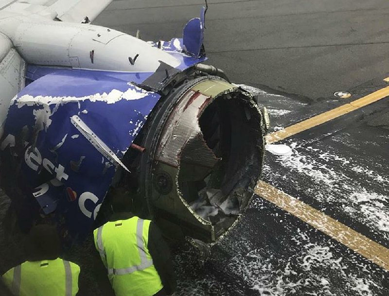 The engine of a Southwest Airlines plane is inspected on a runway at the Philadelphia International Airport where the aircraft made an emergency landing Tuesday. 