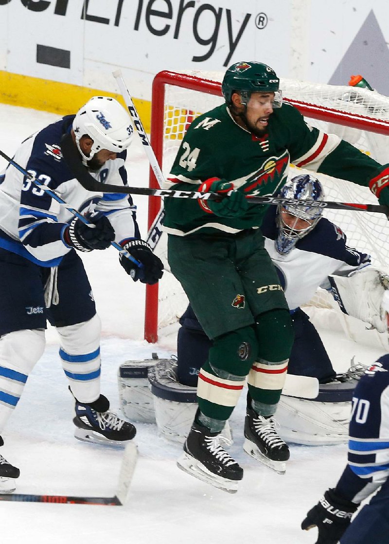 Matt Dumba of the Minnesota Wild jumps for a shot Tuesday night as Winnipeg Jets goalie Connor Hellebuyck (right) looks on during the Jets’ 2-0 victory over the Wild. Winnipeg leads the series 3-1.  