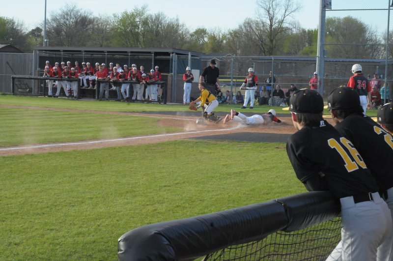 MARK HUMPHREY ENTERPRISE-LEADER Both dugouts are riveted as a Farmington runner scores during the Cardinals' 12-9 win Monday, April 16, over rival Prairie Grove in the diamond version of the 'Battle of 62.'