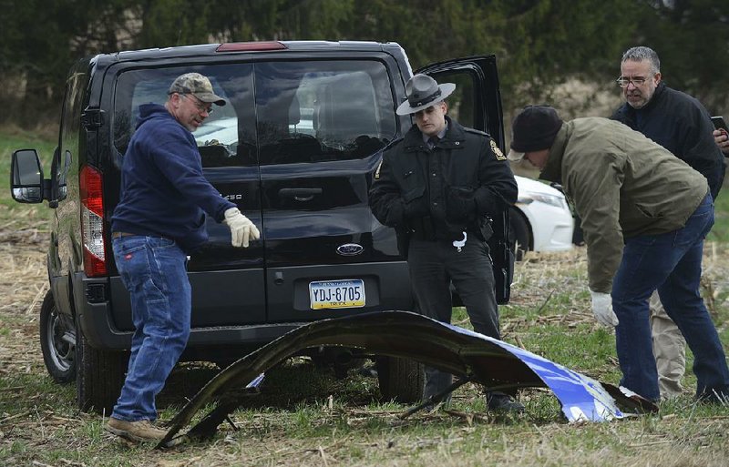 Pennsylvania Game Commission employees examine a piece of engine covering Wednesday that fell from a Southwest Airlines plane into a Penn Township field Tuesday.  